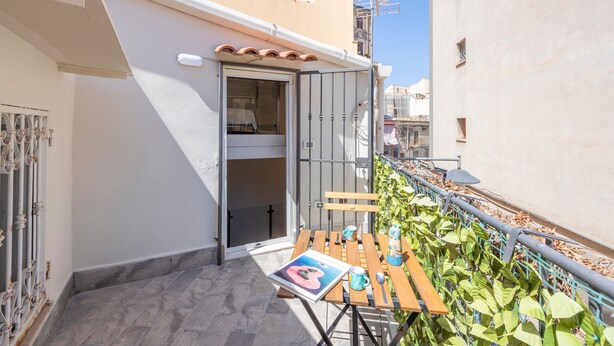 A balcony with a table, chairs, and a magazine.