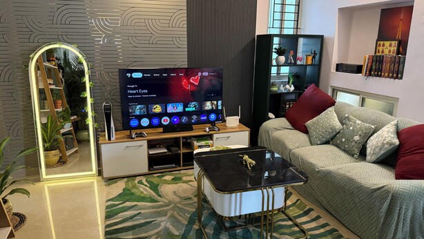 A modern living room with a flat-screen TV, a sofa, a coffee table, and a bookshelf.