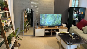 A modern living room with a flat-screen TV, a coffee table, a sofa, and a bookshelf.