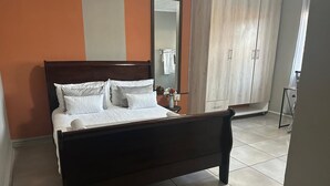A bedroom with a wooden bed, a nightstand, a mirror, and a wardrobe.