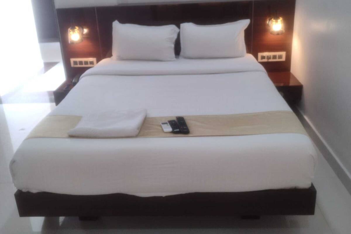 A neatly made bed with white linens, a wooden headboard, and bedside lamps.