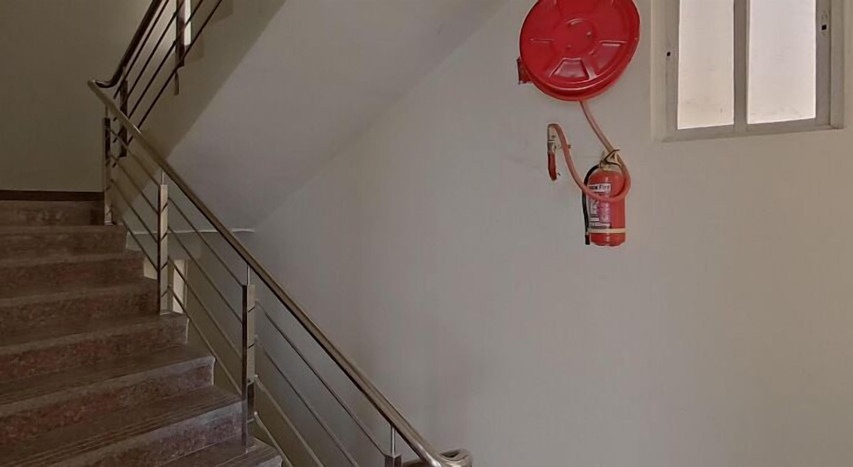 Eine Treppe mit Metallgeländer und einem roten Feuerlöscher an der Wand.