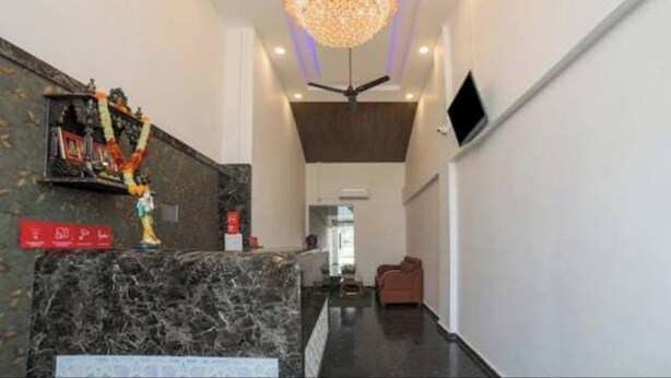 Un hall d’hôtel avec un comptoir d’accueil en marbre, un lustre, un ventilateur de plafond et un téléviseur fixé au mur.