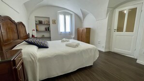 A bedroom with a wooden bed, a wardrobe, a small window, and a door. - Ancient House by Wonderful Italy (Sanremo)