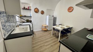 A compact kitchen with a sink, stove, and dining table. - Ancient House by Wonderful Italy (Sanremo)