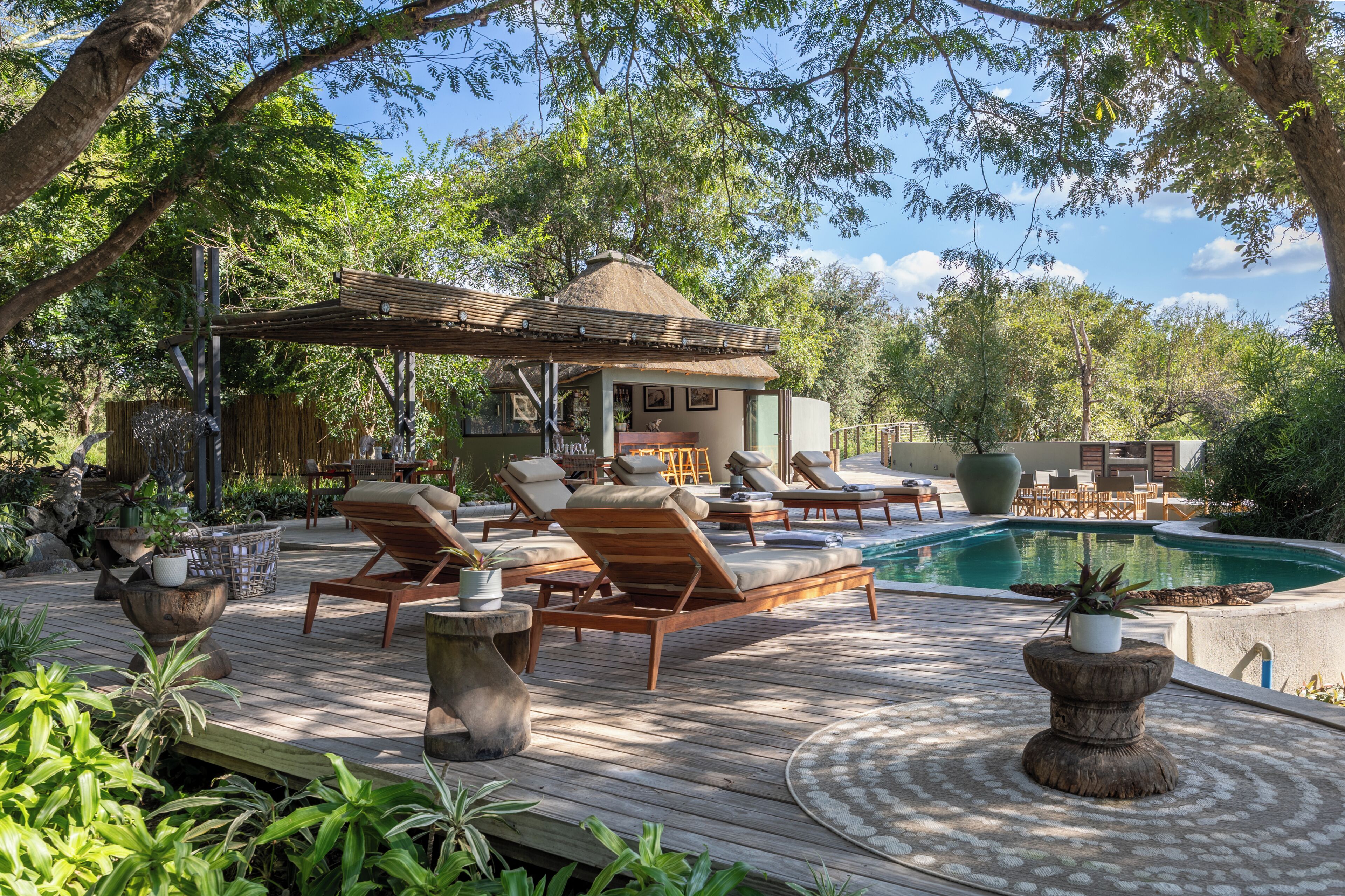 A wooden deck with lounge chairs, a pool, and a gazebo.