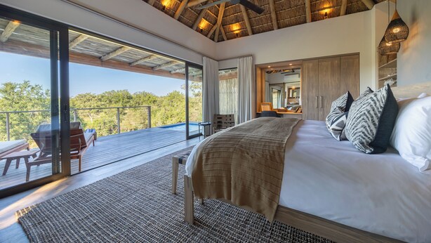 A bedroom with a large bed, a ceiling fan, and a view of the outdoors. - Klaserie Drift Amani (Klaserie Private Nature Reserve)
