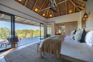 Un dormitorio con una cama grande, un ventilador de techo y vistas al exterior.