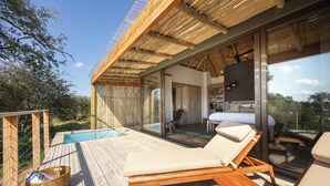A wooden deck with a pool, lounge chairs, and a glass-enclosed dining area. - Klaserie Drift Amani (Klaserie Private Nature Reserve)