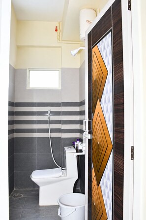 Un baño con inodoro, ducha y ventana.