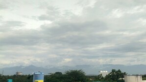 A cloudy sky with mountains in the background and a water tank in the foreground. - SRI NAVANEETHA KRISHNA MAHAL & RESIDENCY (Andipatti)