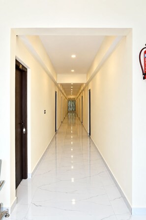 Un pasillo largo y estrecho con suelo pulido y puertas a ambos lados.