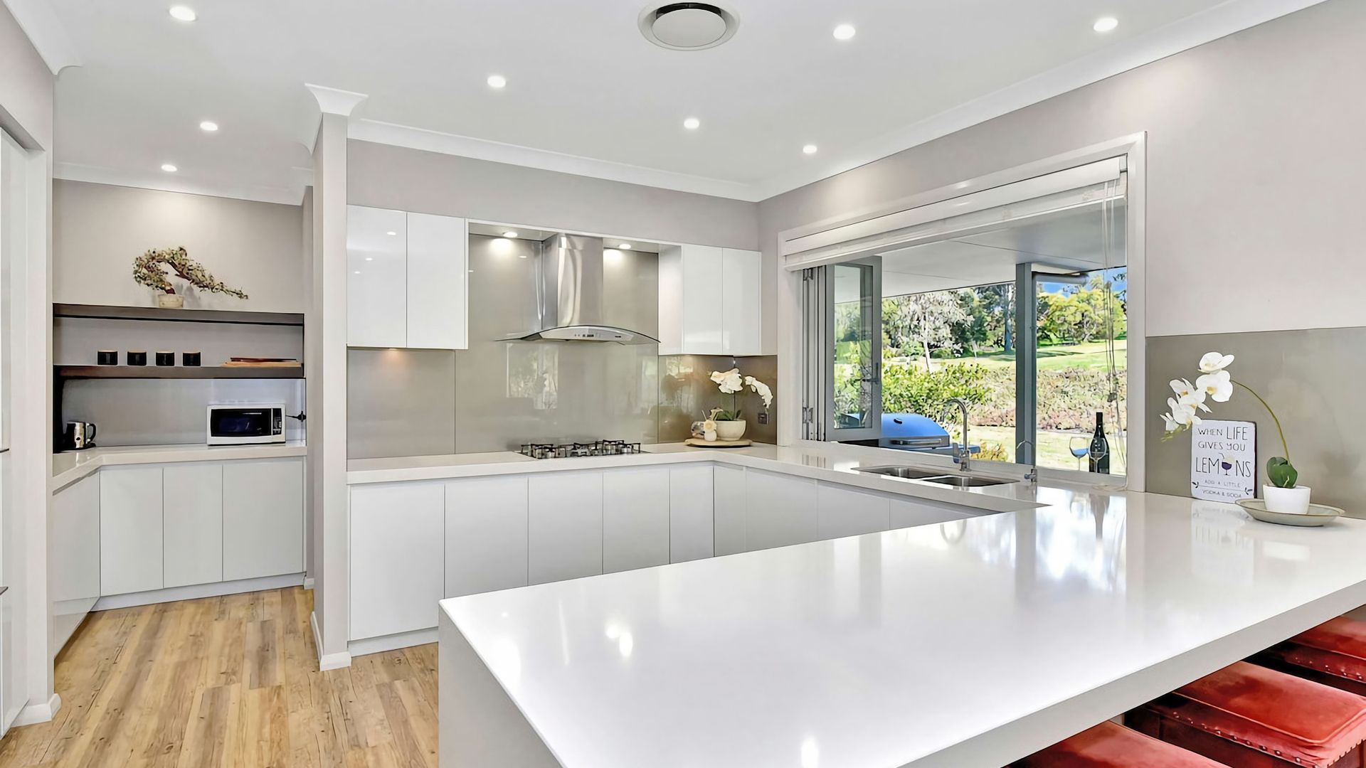 A modern kitchen with white cabinetry, a central island, and a view of the outdoors.