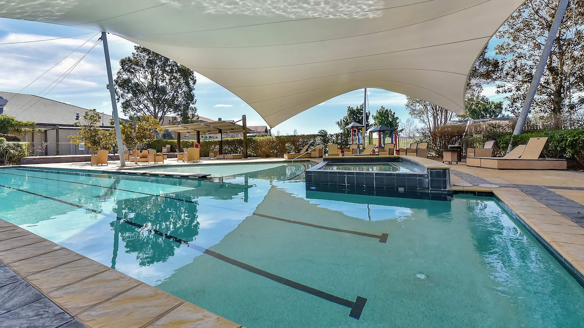 Une piscine dotée d’une structure servant de parasol, de chaises longues et d’un espace équipé d’un jacuzzi.