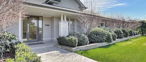 A modern two-story building with a stone facade, a covered entrance, and a well-maintained lawn.