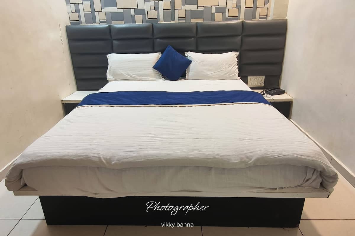 A bed with a white mattress, a blue blanket, and a grey headboard.