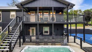 A two-story building with a balcony, a hot tub, and a basketball court.
