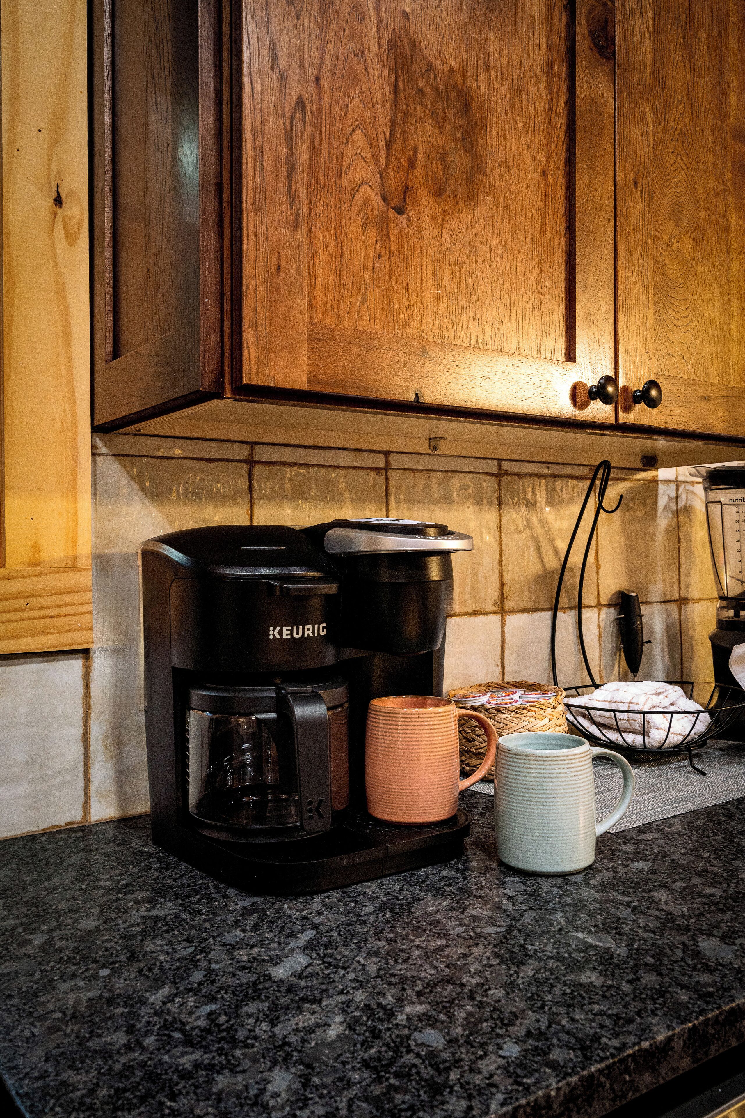 Keittiössä on puiset kaapit, Keurig-kahvinkeitin ja kaksi mukia työtasolla.