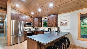 A modern kitchen with wooden cabinets, stainless steel appliances, and a large island with bar stools.