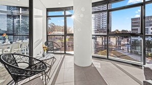 A modern interior with large windows, a round table, and two chairs.