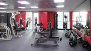Une salle de sport équipée de divers appareils d’entraînement, notamment des machines à poids et des poids libres.