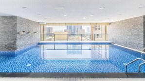 Une piscine intérieure moderne offrant une vue dégagée sur les gratte-ciel de la ville grâce à de grandes fenêtres.