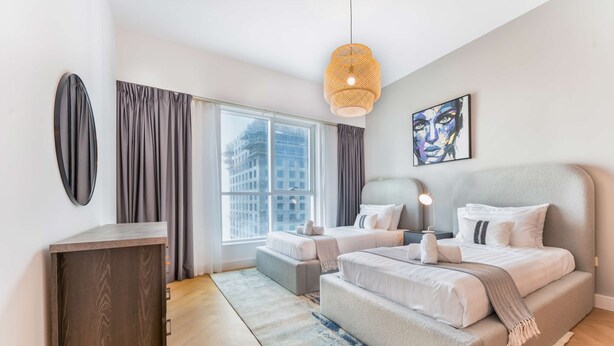 Une chambre moderne avec un grand lit, des tables de chevet, un bureau et une fenêtre avec des rideaux.