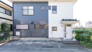 A two-story building with a dark grey and white facade, multiple windows, and a small porch area. - K&K HOUSE (Takasaki)