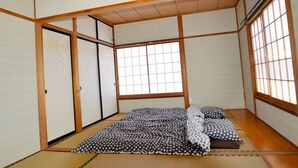A traditional Japanese room with tatami flooring, shoji screens, and a futon bed. - K&K HOUSE (Takasaki)