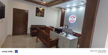 Un área de recepción con un banco de madera, un mostrador con una computadora y un letrero en la pared.