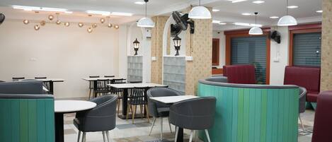 A modern dining area with tables and booths, ceiling fans, and pendant lighting.