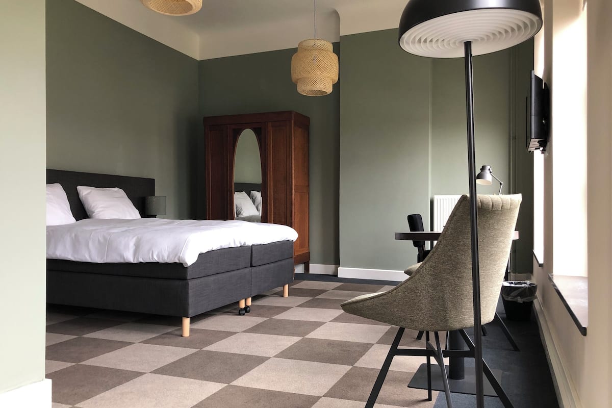 Un dormitorio con cama, una silla, un escritorio y un espejo.