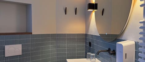 Un baño moderno con inodoro blanco, lavamanos con espejo y un perchero para toallas.
