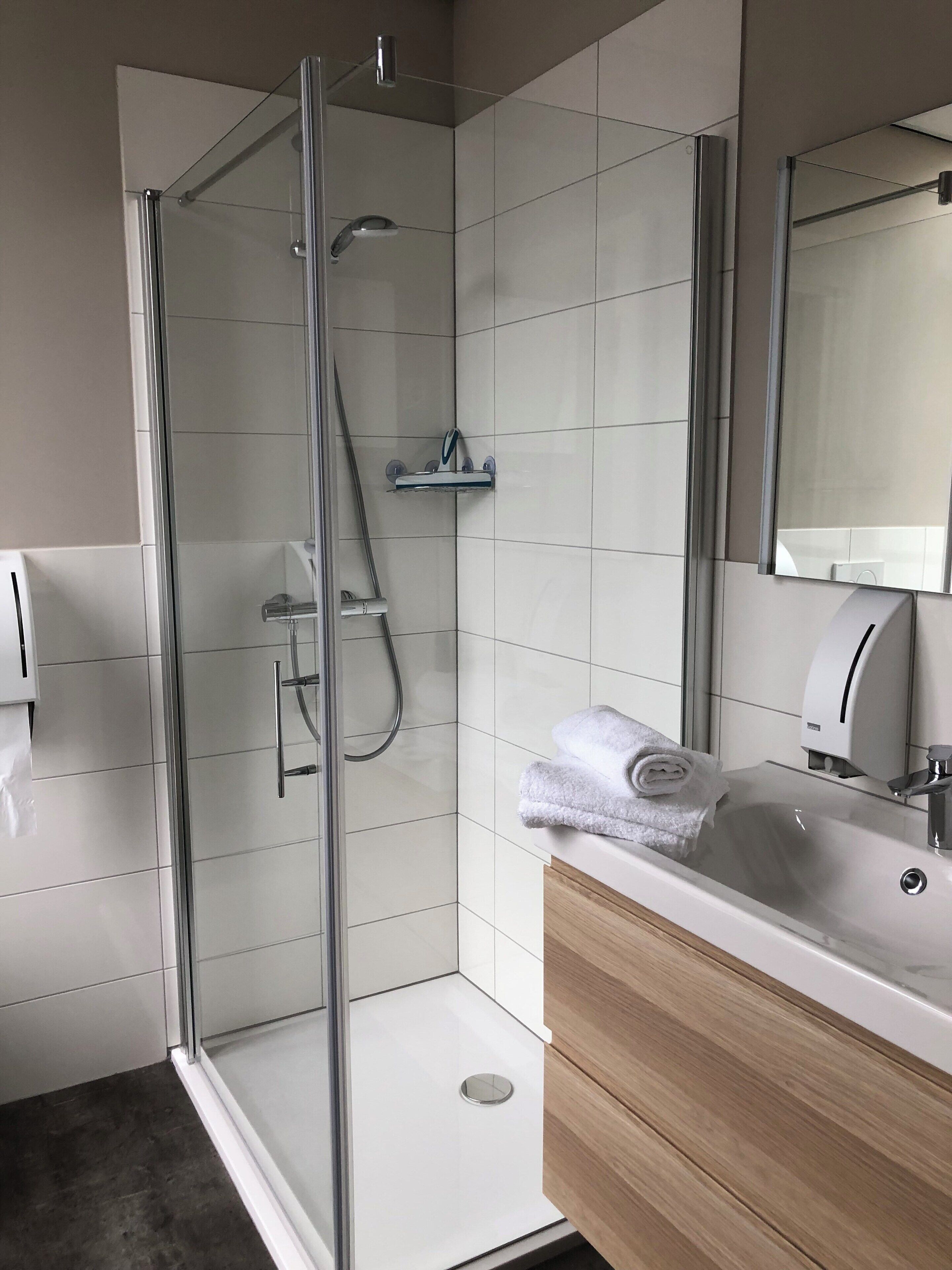 A modern bathroom with a glass-enclosed shower, a sink with a mirror, and a towel rack.