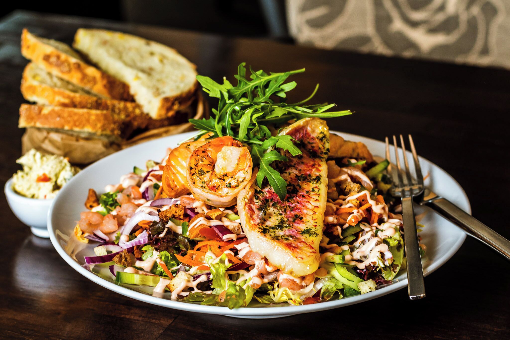A plate of food with shrimp, greens, and bread.