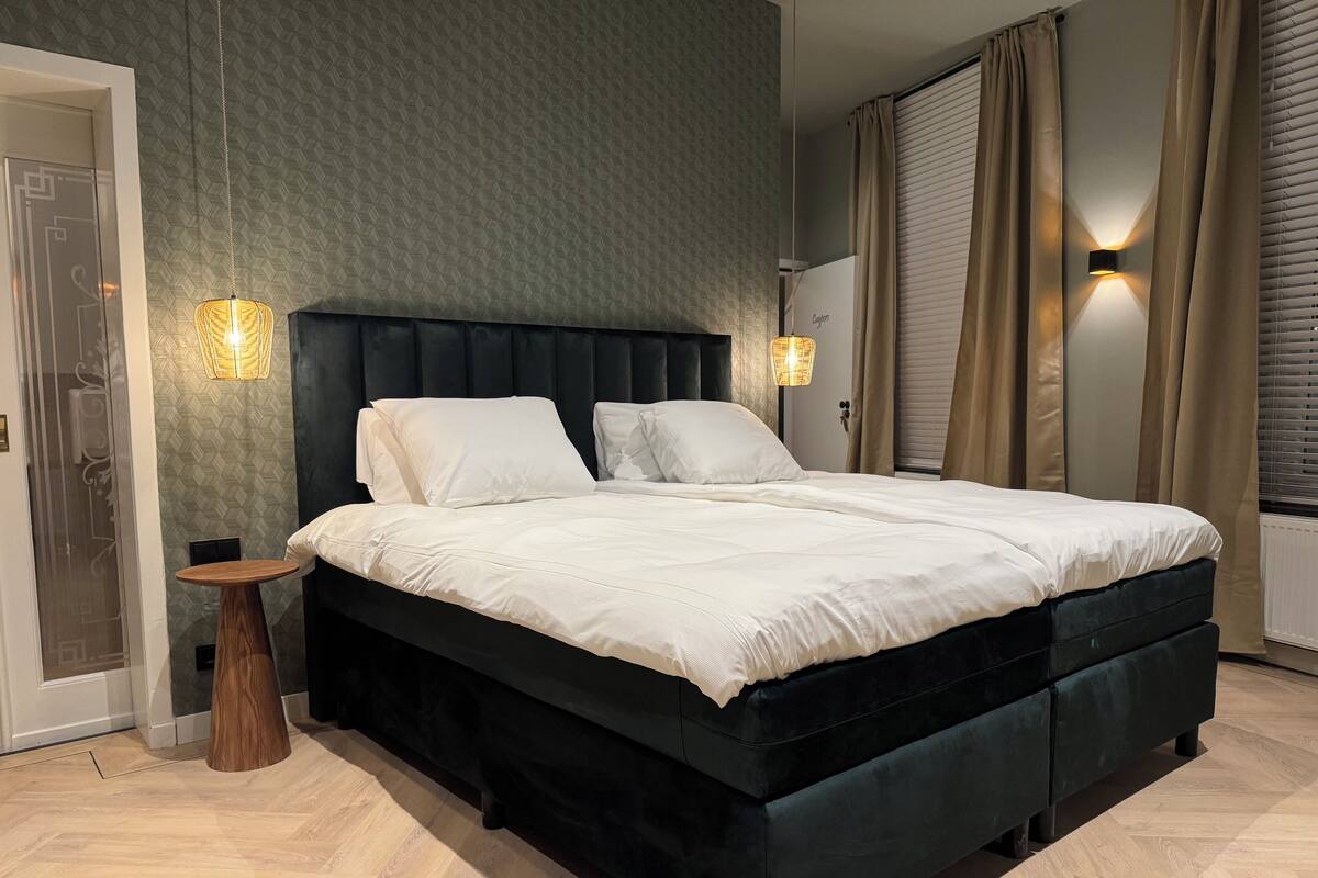 Un dormitorio moderno con una cama grande, dos lámparas de noche y una pequeña mesita de madera.