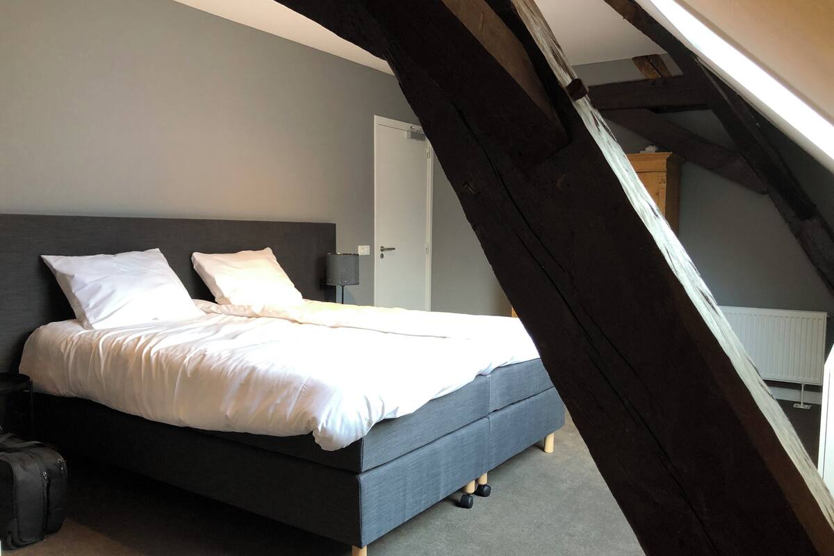 Un dormitorio con cama, mesita de noche, lámpara y puerta.