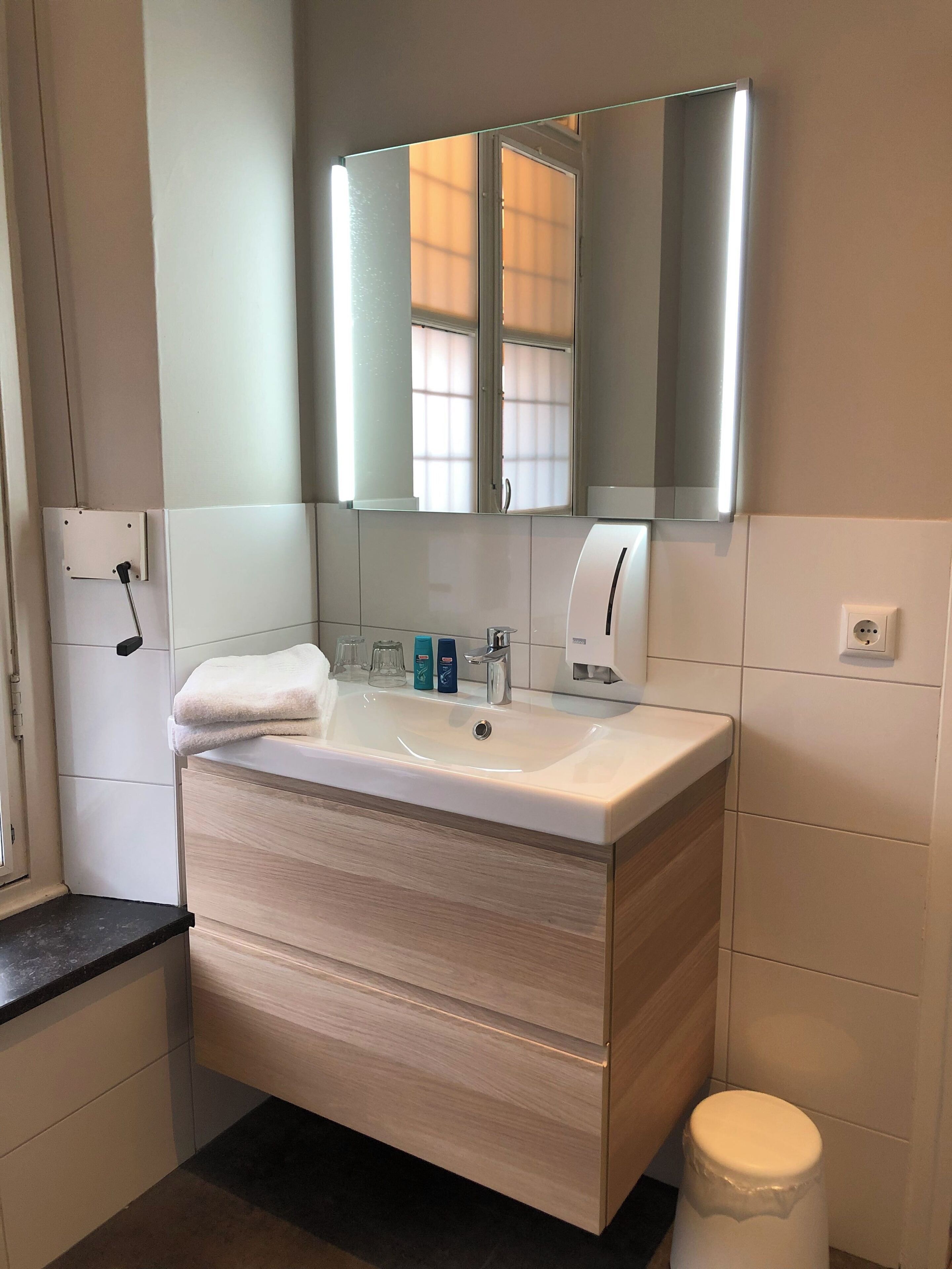 A modern bathroom with a white vanity, a mirror, and a toilet.