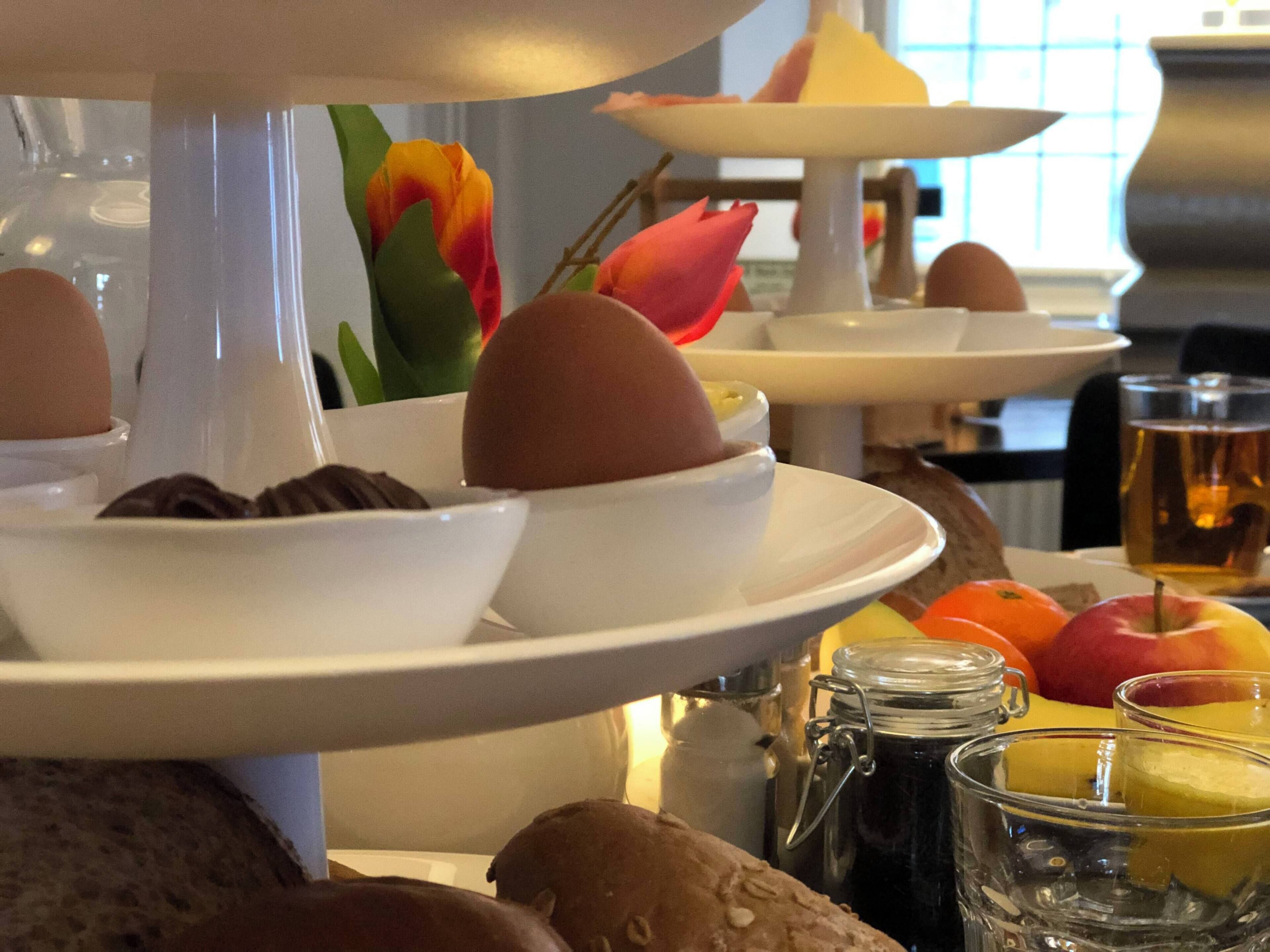 Un bufé de desayuno con diversas opciones de comida y un jarrón decorativo de tulipanes.