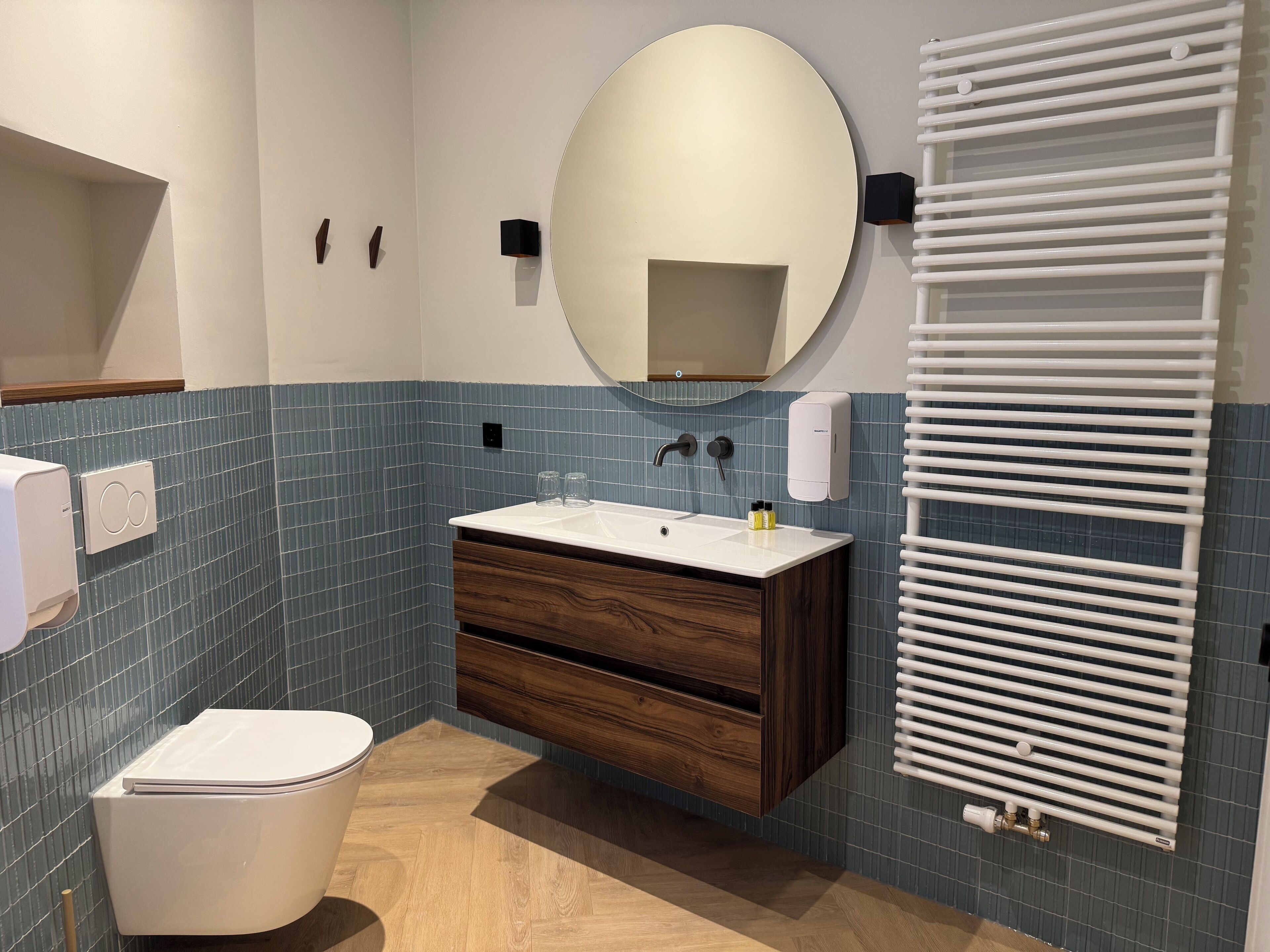 Une salle de bain moderne avec des toilettes blanches, un meuble-lavabo en bois et un grand miroir.
