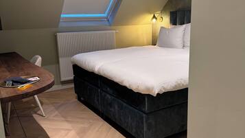 Un dormitorio con cama, escritorio, radiador y tragaluz.