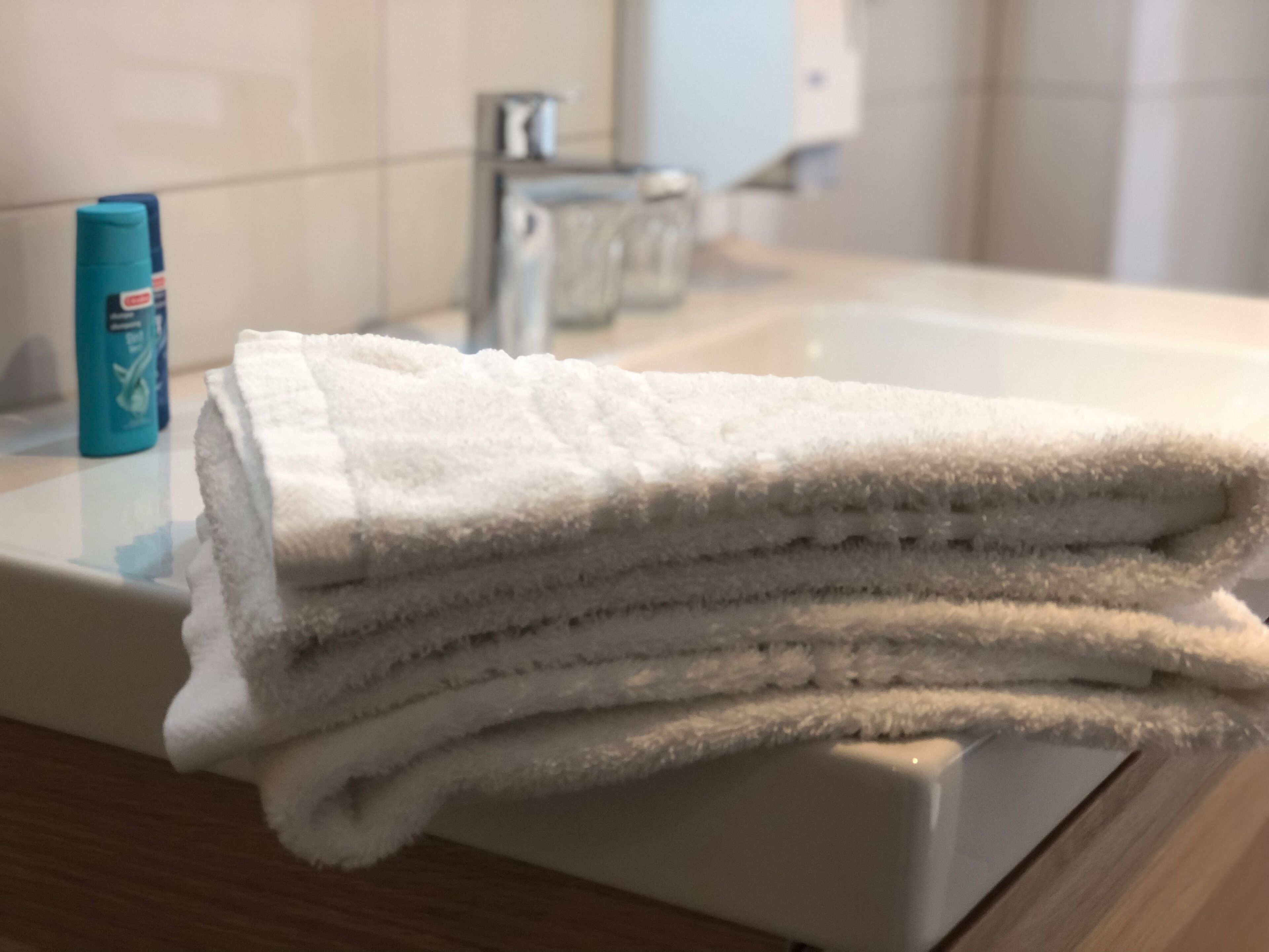 Une pile de serviettes blanches est posée sur le comptoir de la salle de bain.