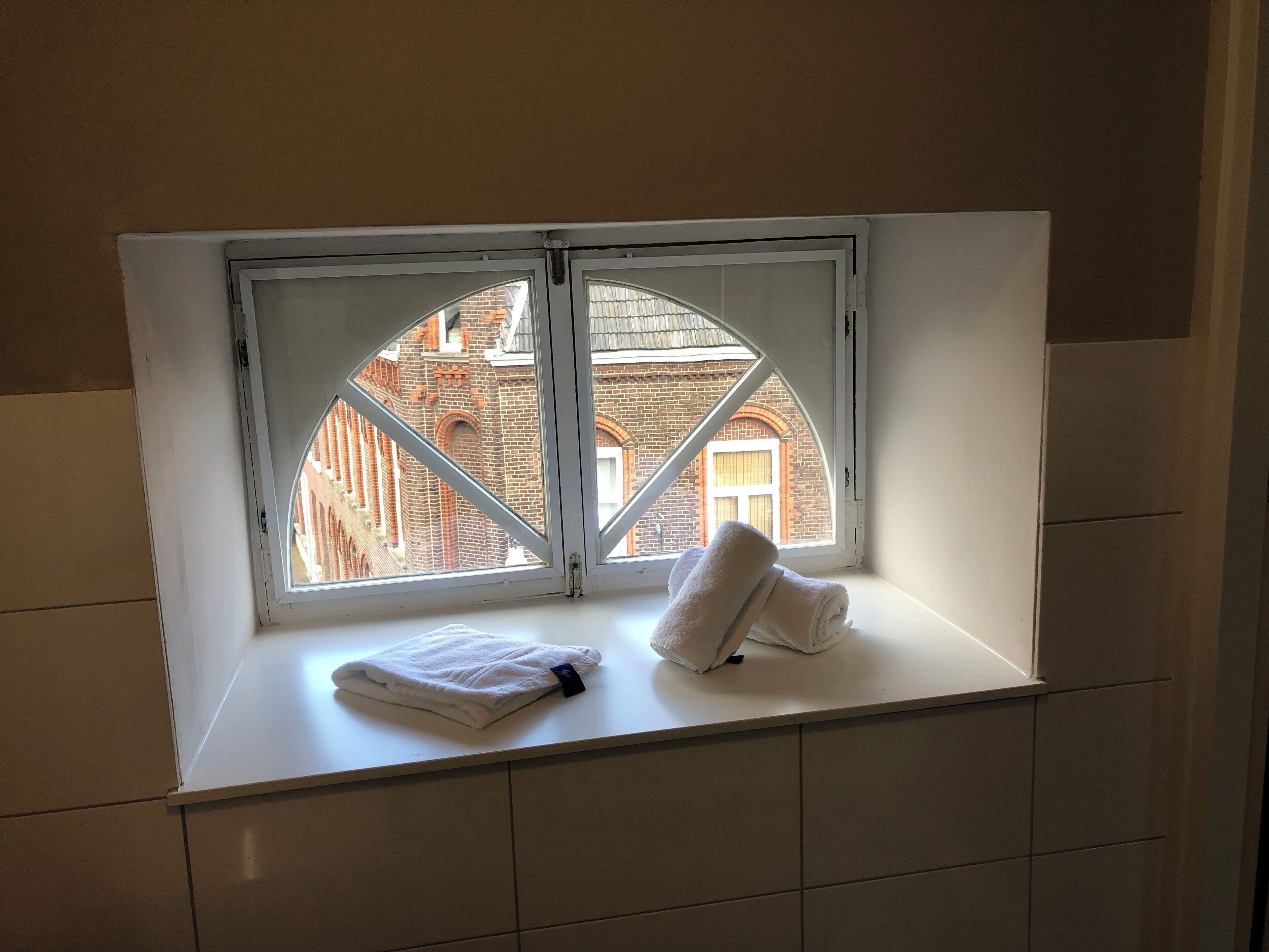 Ein Badezimmer mit Fenster, Handtuch und gefliesten Wänden.