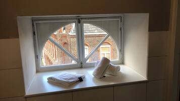 Ein Badezimmer mit Fenster, Handtuch und gefliesten Wänden.