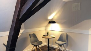 Ein kleiner Raum mit zwei Stühlen, einem Tisch und einer Stehlampe.