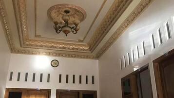 A room with a decorative ceiling, wooden doors, and a clock.