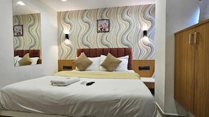 Un dormitorio con una cama, un armario de madera, un espejo y una pared con diseño ondulado.