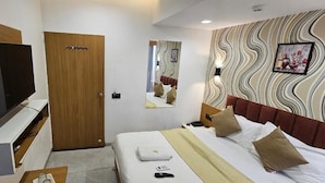 Habitación de hotel con cama, televisión, armario, espejo y pared con diseño ondulado.