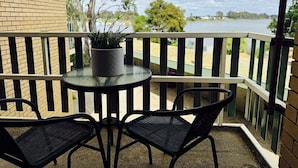 Ein Balkon mit Tisch und zwei Stühlen mit Blick auf einen Fluss.