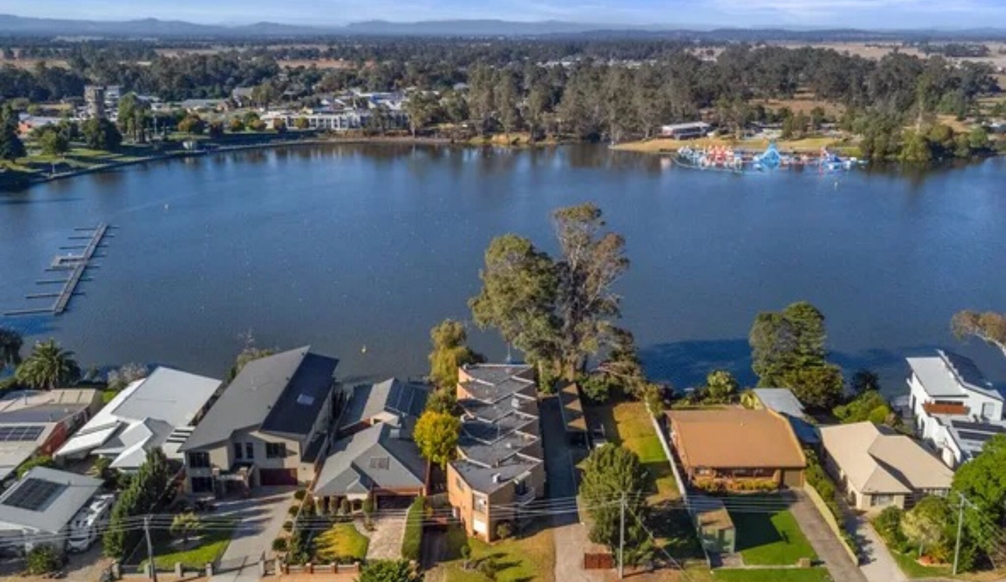 A residential area with modern houses, a dock, and a lake.